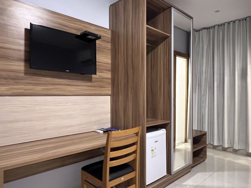 Interior do quarto superior com televisão, frigobar, mesa de escritório e armário de roupas no Hotel Araguaia de Palmas, capital do Tocantins, no Brasil.