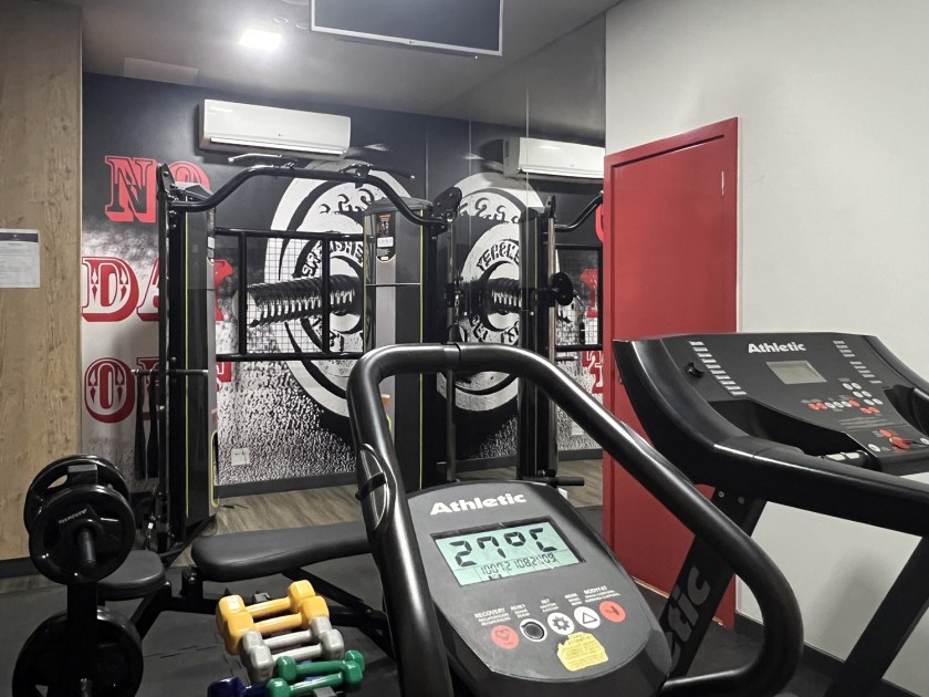 Ambiente pequeno com equipamentos de academia.