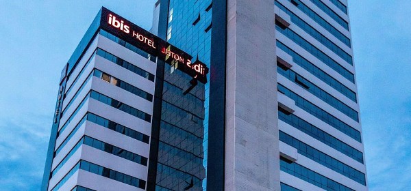 Fachada de prédio com muitos andares com letreiro do hotel ibis.
