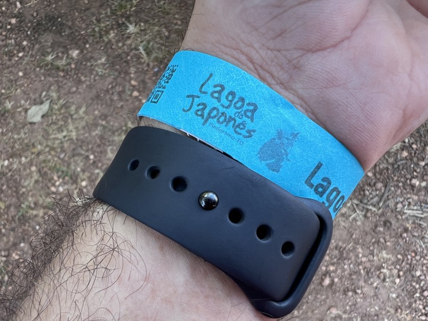 Pulso com pulseira azul de papel escrito Jagoa do Japonês e pulseira de relógio preta.