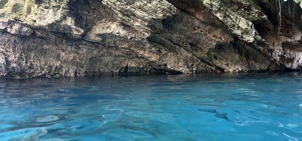 Foto com água da lagoa transparente e azul na metade inferior e rocha na parte superior.