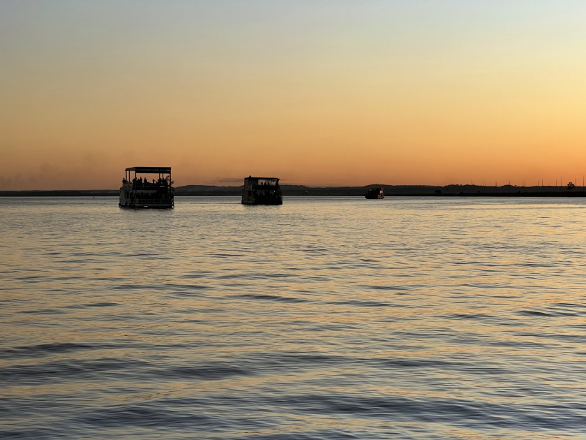 Barcos flutuantes navegando no lago com luz do fim do dia.