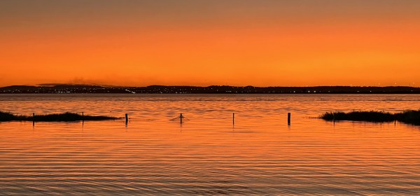 Fim de pôr-do-sol sobre as águas do lago com o céu bem avermelhado.